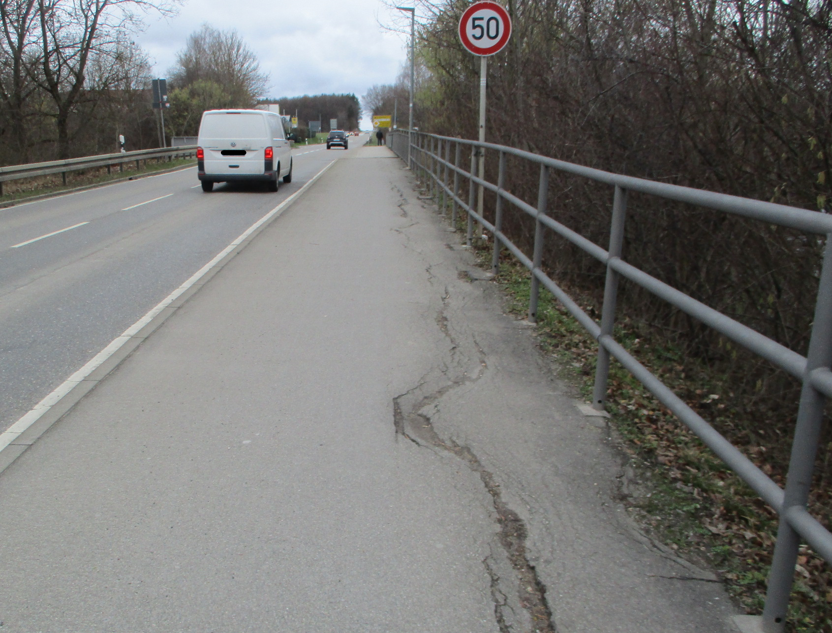 Das Bild zeigt die L 374 bei Riederich; Leitplanken, sanierungsbedürftiger Radweg, Fahrzeuge, Verkehrsschild