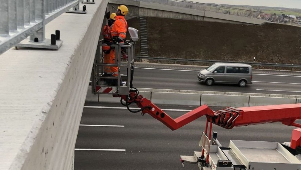 Eine Brücke auf der Autobahn wird mit Hilfe eines Krans geprüft