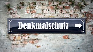 Das Foto zeigt die eine Mauer an der ein Schild befestigt ist mit dem Schriftzug "Denkmalschutz"