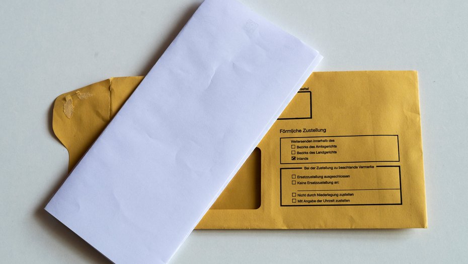 Kuvert mit Briefbogen Ein gefalteter Briefbogen liegt auf einem Kuvert, auf dem Persönliche Zustellung steht.