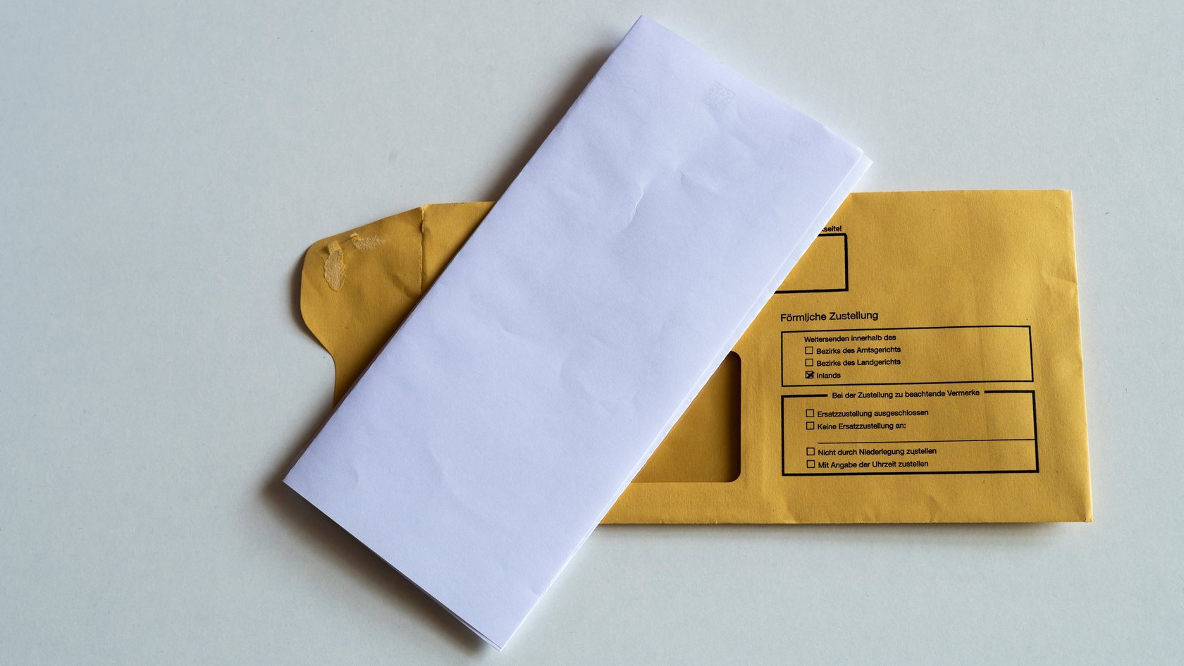 Kuvert mit Briefbogen Ein gefalteter Briefbogen liegt auf einem Kuvert, auf dem Persönliche Zustellung steht.