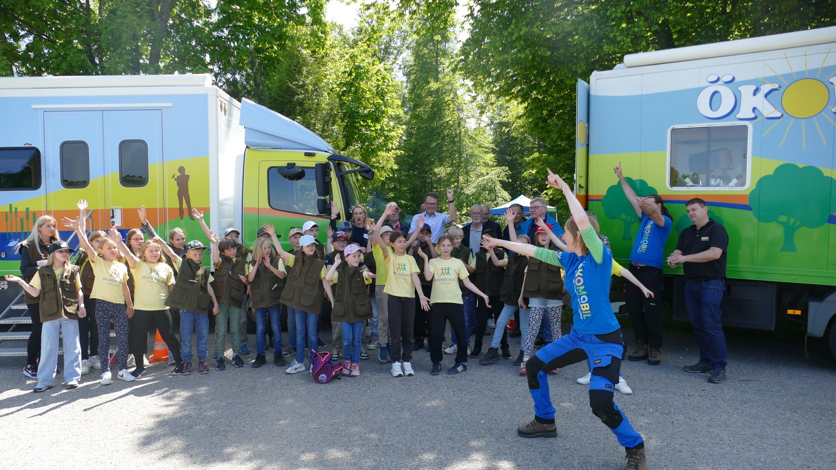 Kinder und Erwachsene sind vor den zwei Ökomobilen abgebildet.