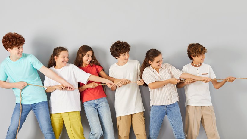 sieben Jungen und Mädchen ziehen am Seil
