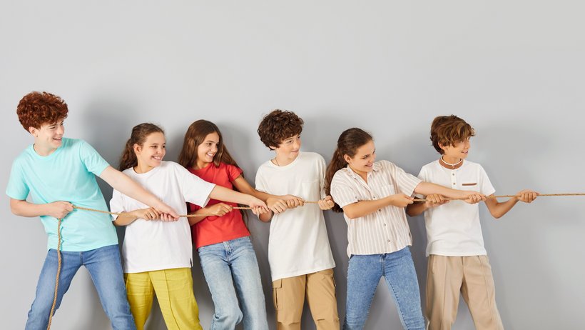 sieben Jungen und Mädchen ziehen am Seil