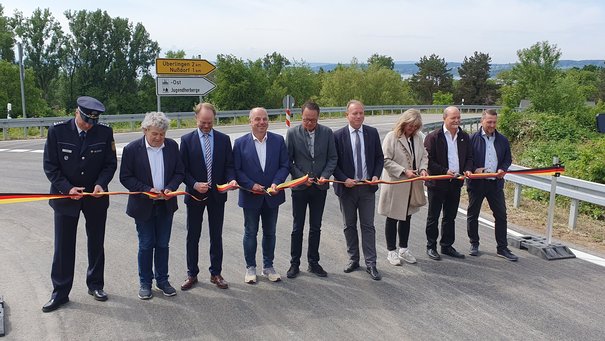 Mehrere Personen durchschneiden ein Band, dass in den Farben der Deutschland-Flagge schwarz rot gold gestreift ist. 