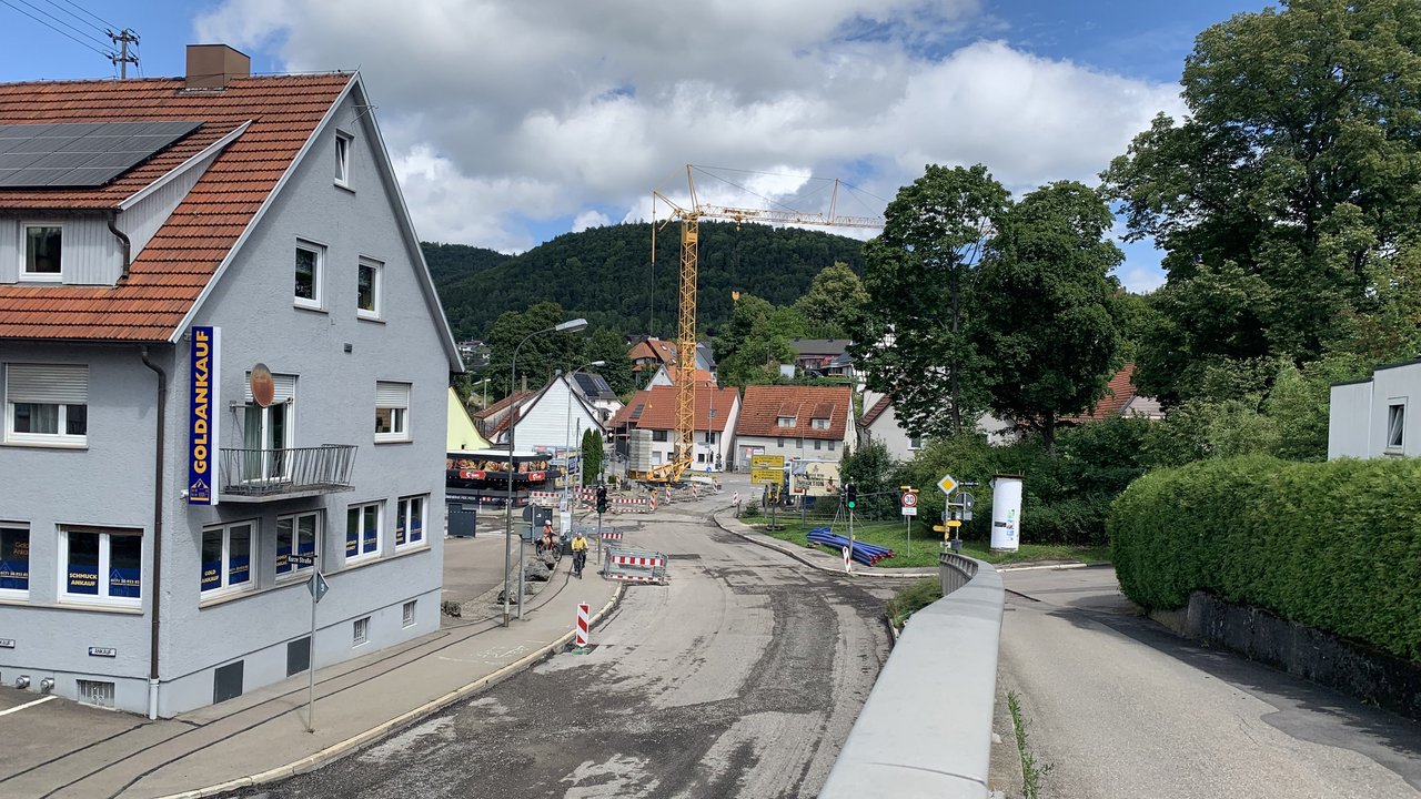Das Foto zeigt die Baustelle in der Ortsdurchfahrt Albstadt-Lautlingen. Mehrer Absperrungen, ein Baukran und Baustellenmaterial am Rand der Fahrbahn.