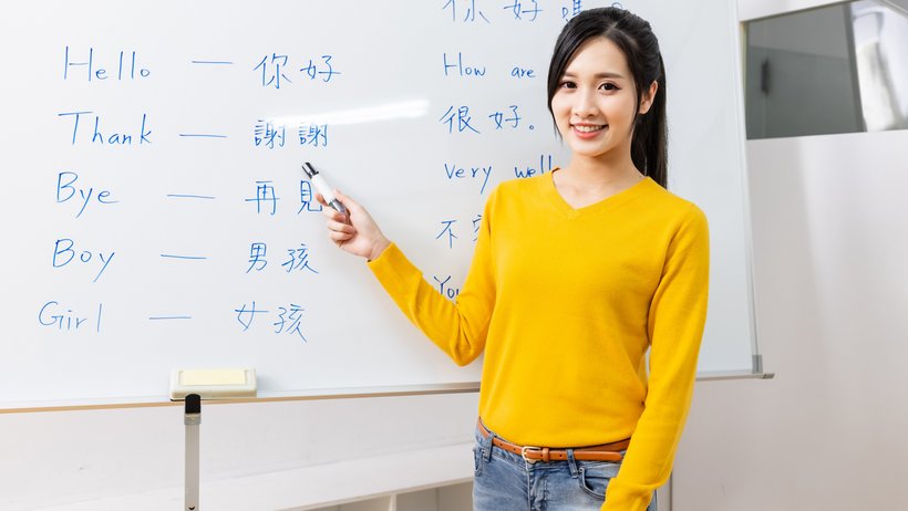 Eine Lehrerin für Chinesisch steht vor einer Tafel mit Vokabeln