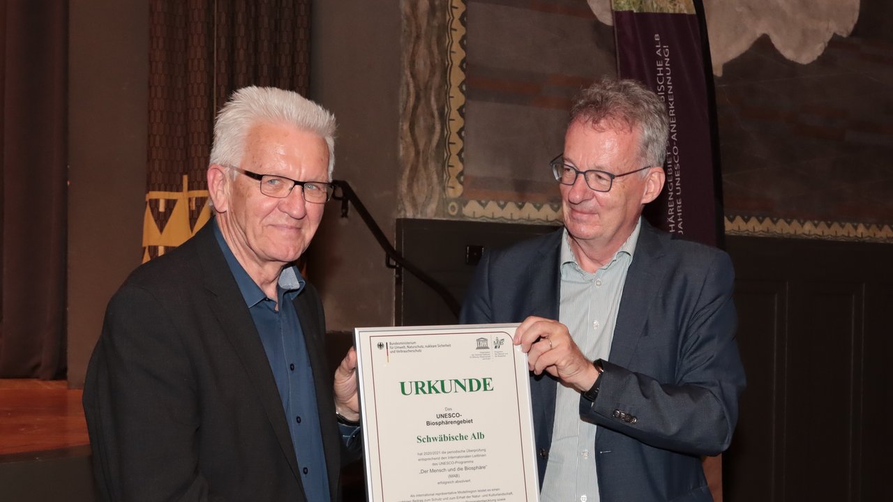 Das Bild zeigt Herrn Ministerpräsidenten Winfried Kretschmann und Dr. Stefan Lütkes bei der Urkundenübergabe zur Erneuerung der UNESCO-Auszeichnung des Biosphärengebiets Schwäbische Alb