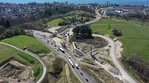 Ein Luftbild einer Baustelle, im Hintergrund der Bodensee. Auf der Baustelle sind zwei große Betonwände sichtbar, zischen denen Kräne ein Stahlgerüst aufbauen.