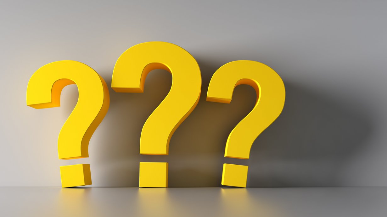 Drei Fragezeichen in Gelborange stehen an der Wand