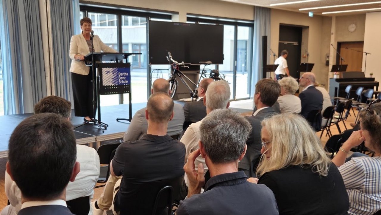 Abteilungsleiterin Dr. Susanne pacher steht auf einem Podium, im Vordergruns blickt man auf das Publikum