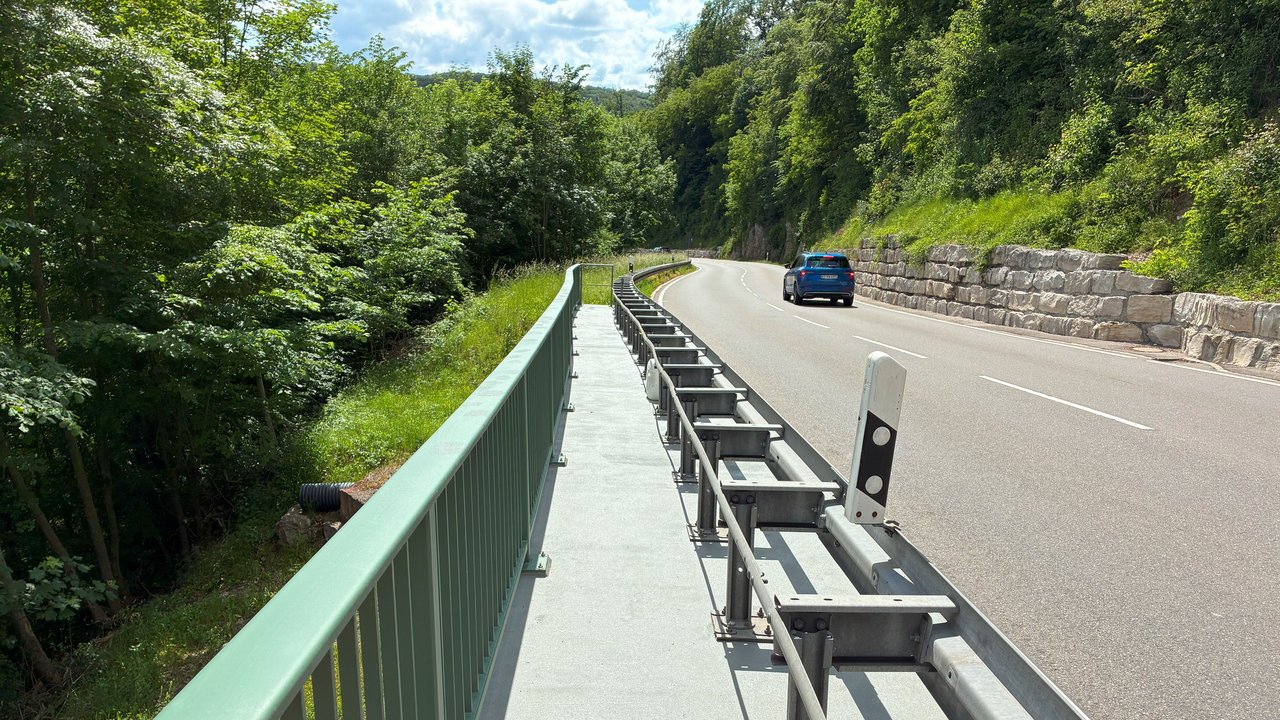 Das Foto zeigt die Böhringer Steigt. Auf der linken Seite sieht man einen Notgehweg und Stützbauwerke. Rechts ist der Hang durch eine Steinmauer gesichert.