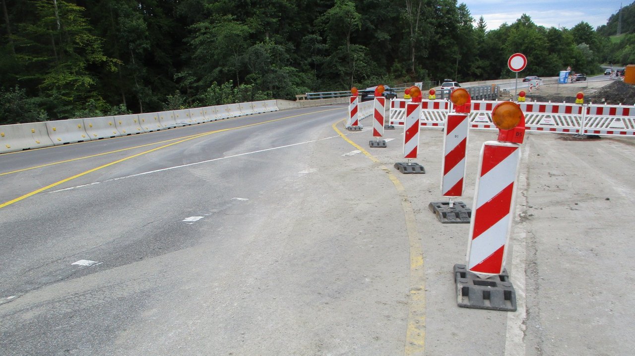 Das Foto zeigt eine Straßenbaustelle, die teilweise abgesperrt ist durch Stehlen