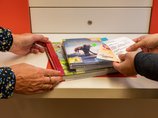 Stadtbücherei Ehingen an der Donau - Verbuchung Vier Hände halten CDs und Bücher an den Selbstverbucher der Stadtbücherei Ehingen an der Donau