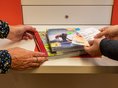 Stadtbücherei Ehingen an der Donau - Verbuchung Vier Hände halten CDs und Bücher an den Selbstverbucher der Stadtbücherei Ehingen an der Donau