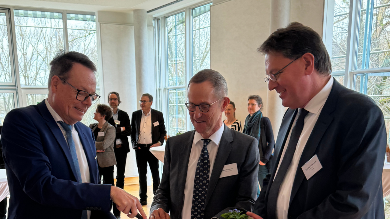 Das Foto zeigt Regierungspräsident Klaus Tappeser, den früheren Abteilungsleiter Peter Goossens und den aktuellen Leiter der Abteilung Marktüberwachung, Stephan Czarnecki an einem Stehtisch beim Kuchenanschnitt