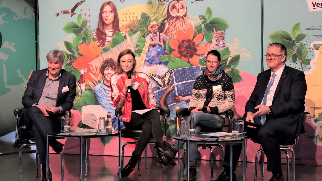Das Bild zeigt die Podiumsdiskussion mit Michael Donth, Achim Nagel sowie Melanie Klock moderiert von Sängerin und Autorin Annie Heger