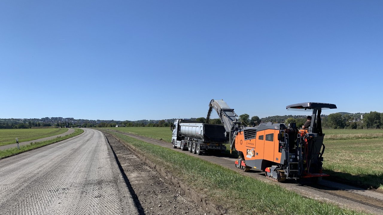 Das Foto zeigt eine Straße während Rückbauarbeiten und zwei Baustellenfahrzeuge