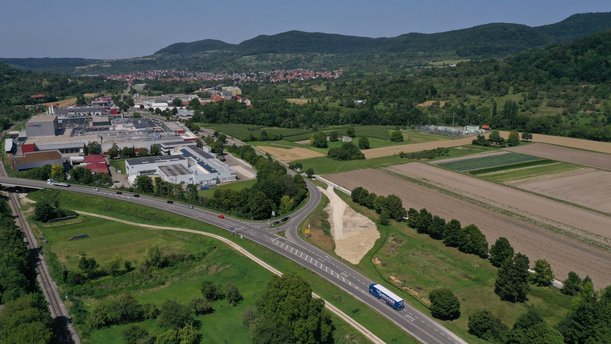 Luftbild einer Kreuzung, neben der große Erdmassen aufgeschüttet sind.
