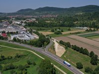 Luftbild einer Kreuzung, neben der große Erdmassen aufgeschüttet sind.