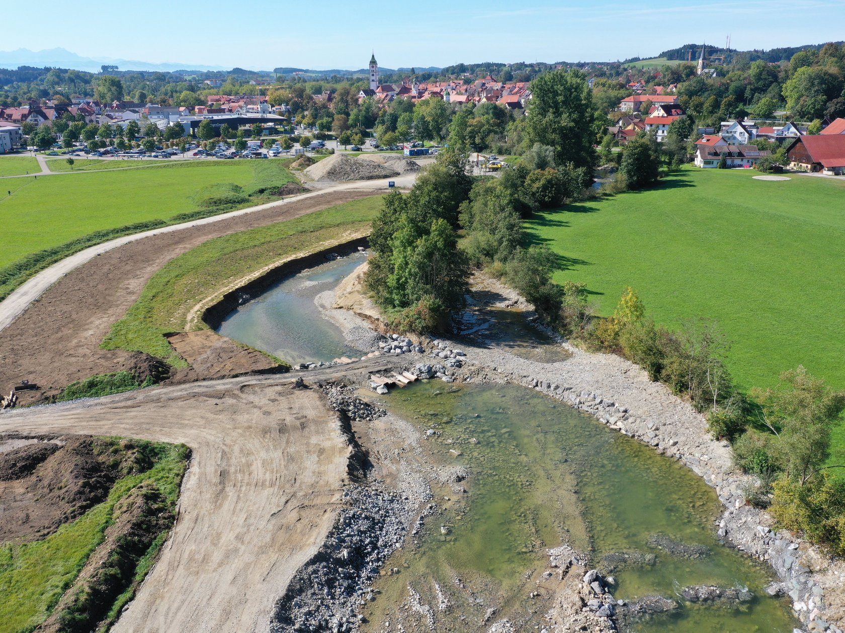 Blick von oben auf den Fluss Argen im Abschnitt 1. Man sieht den geschwungenen Verlauf mit Kiesflächen und Auelandschaft. Im Hintergrund ist die Stadt Wangen zu sehen.