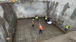 Bauarbeiter stehen in einer Grube und gießen Beton. 