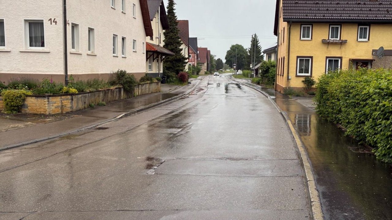 Das Foto zeigt die regennasse Ortsdurchfahrt von Suppingen. Links und rechts sieht man Wohnhäuser.