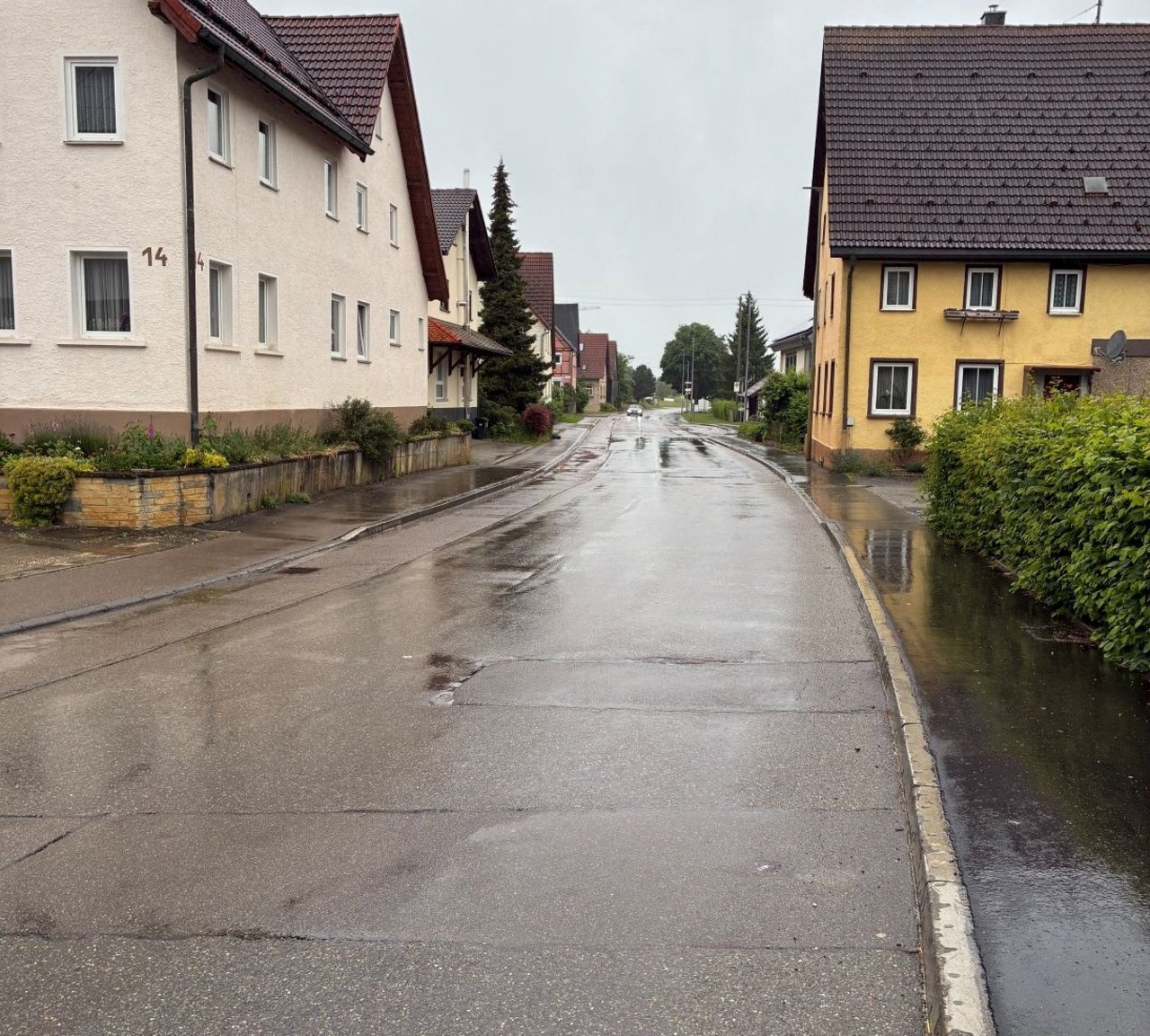 Das Foto zeigt die regennasse Ortsdurchfahrt von Suppingen. Links und rechts sieht man Wohnhäuser.
