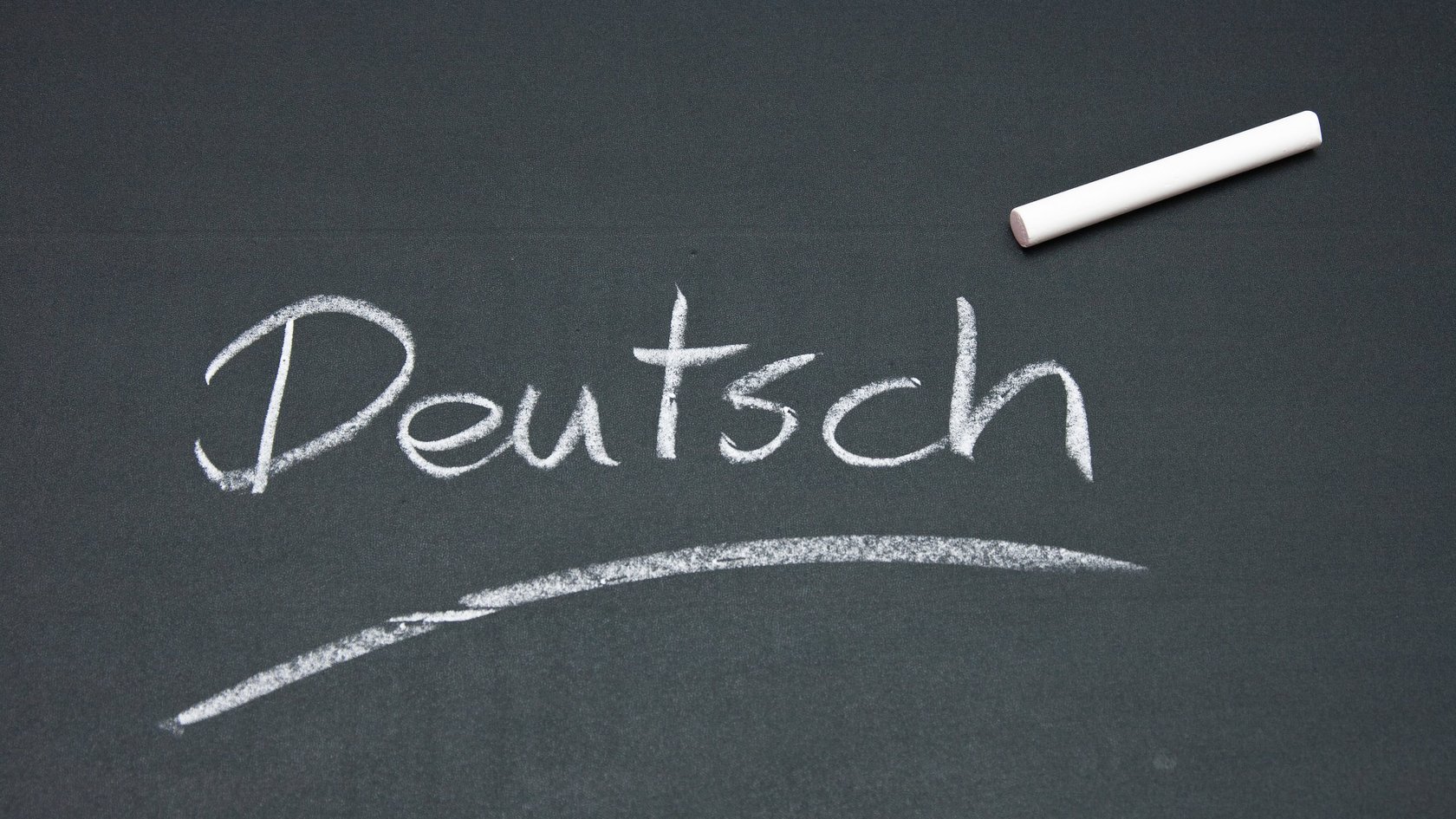 Auf einer grünen Tafelwand steht das Wort "Deutsch".