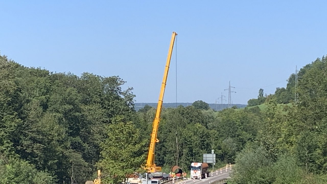 Das Foto zeigt die Brücke über die Eyach westlich von Albstadt-Laufen im Verlauf der B 463. Auf der Baustelle befinden sich mehrere Baustellenfahzeuge und ein Kran. Seitlich der Straße sieht man Wald