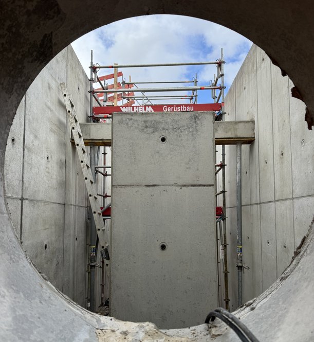 Blick auf eine Baustelle durch einen kreisförmigen Beton-Einlass.