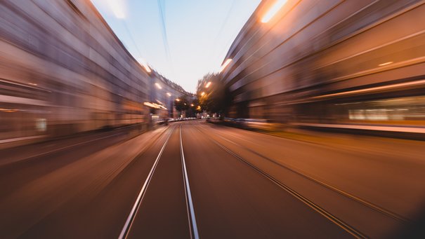 Sonderfahrt mit der S1 durch Ulm, man blickt aus dem Führerhaus der Bahn und sieht vorbeiziehende Häuserfronten (unscharf), Abendstimmung