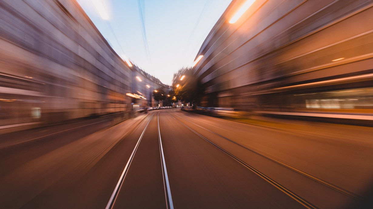 Sonderfahrt mit der S1 durch Ulm, man blickt aus dem Führerhaus der Bahn und sieht vorbeiziehende Häuserfronten (unscharf), Abendstimmung