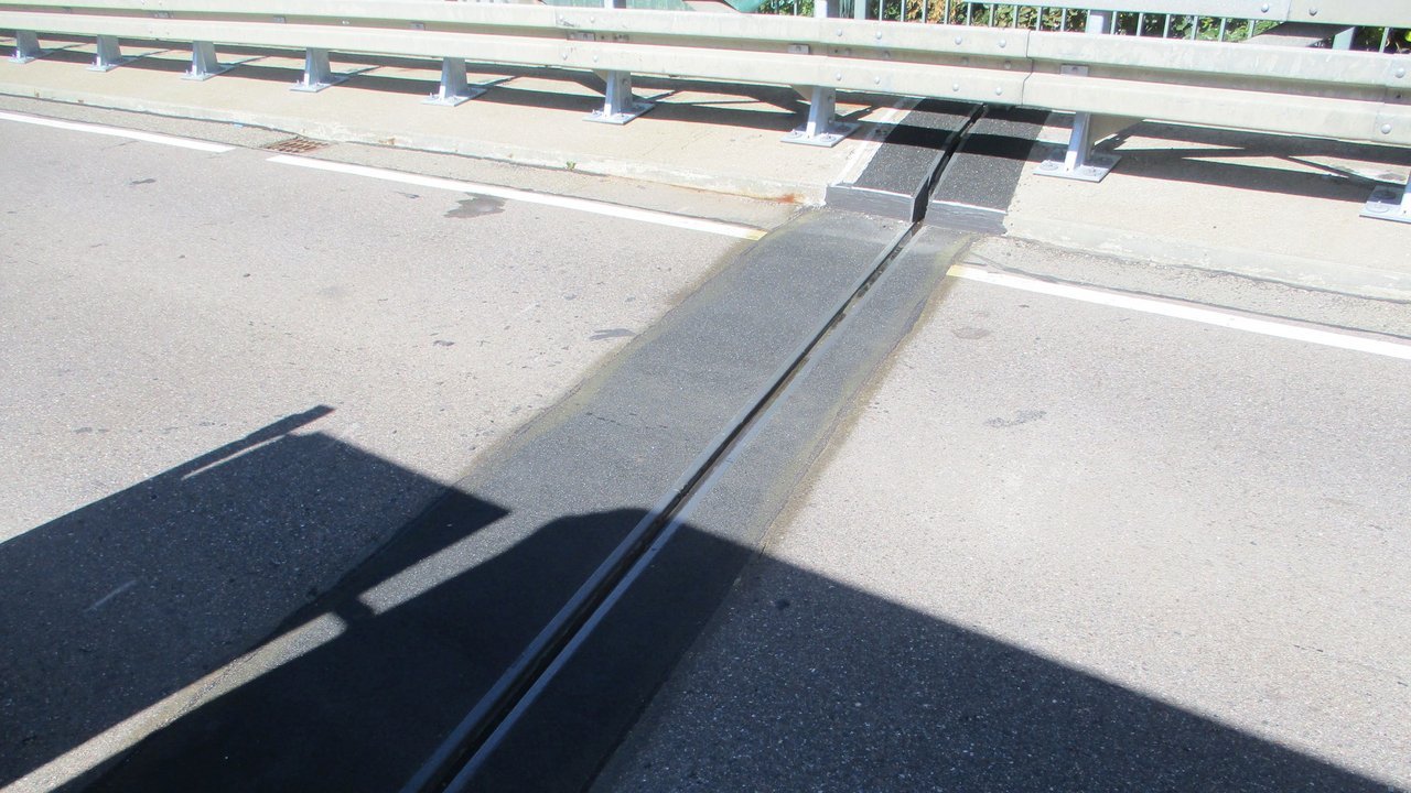 Man sieht den instandgesetzten Belag einer Brücke und die Leitplanken