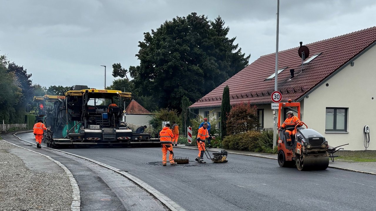 Das Foto zeigt die Erneuerung der Fahrbahn auf der L 285. Man sieht arbeitende Personen und Baustellenfahrzeuge.