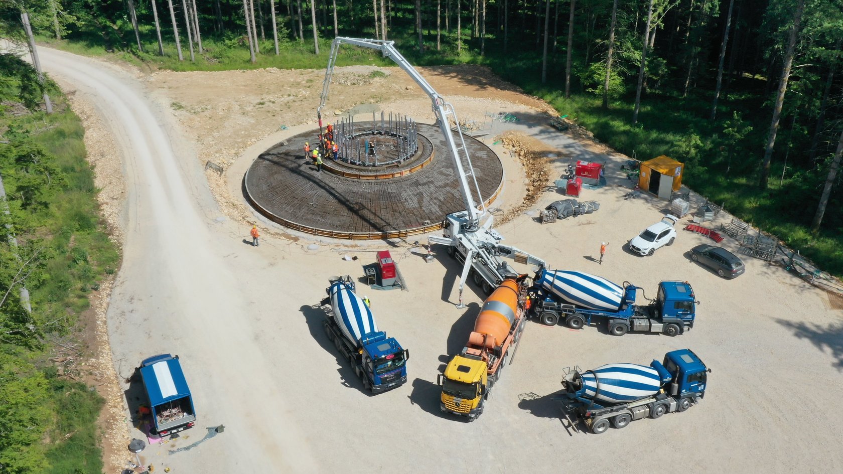 Beton nonstop Blick auf die Baustelle, auf der mehrere Lastwagen stehen, die Beton anliefern.