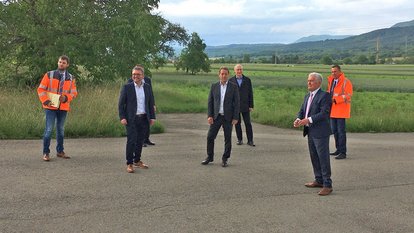 Sieben Vertreter der Straßenbauverwaltung und der Kommunalverwaltung stehen auf der Straße und diskutieren.