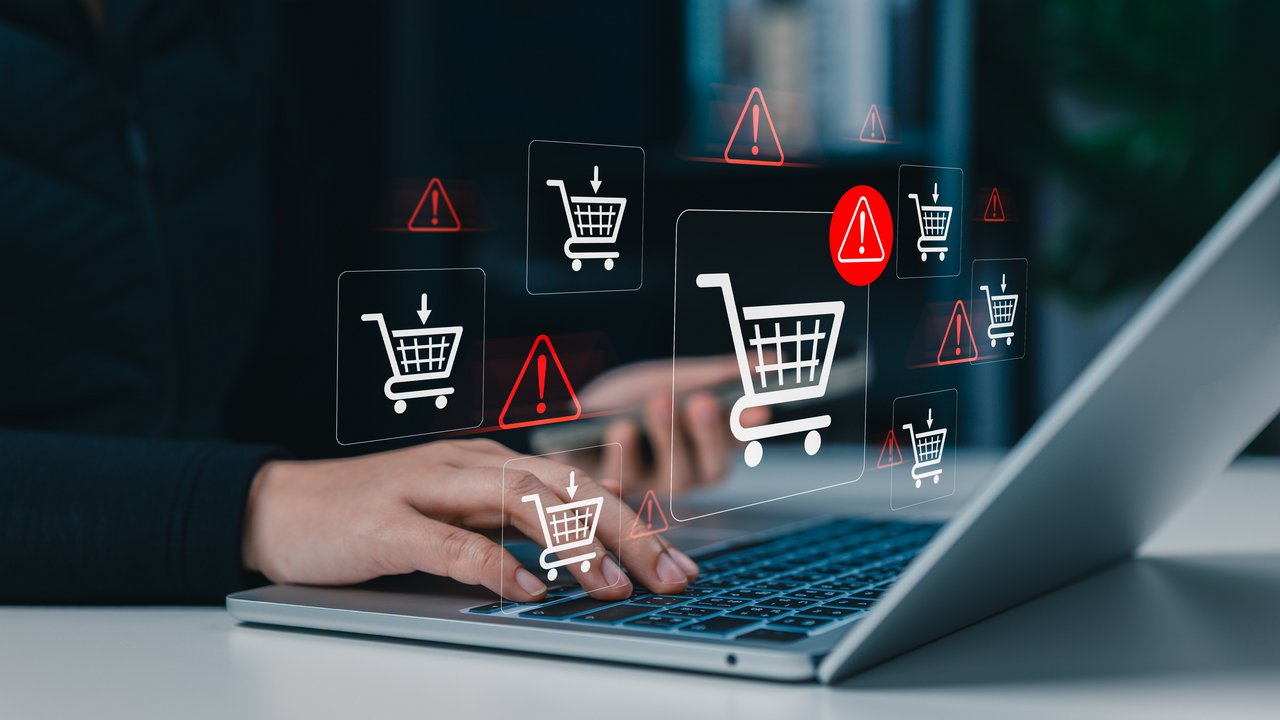 Blick auf eine Hand am Laptop und Icons von Eiunkaufswagen