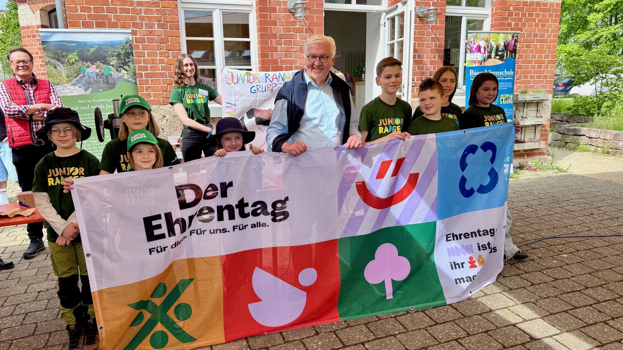 Bundespräsident Steinmeier und Regierungspräsident Tappeser stehen inmitten einer Gruppe von menschen. Bundespräsident Steinmeier hört den Erläuterungen eines Teilnehmers zu. 