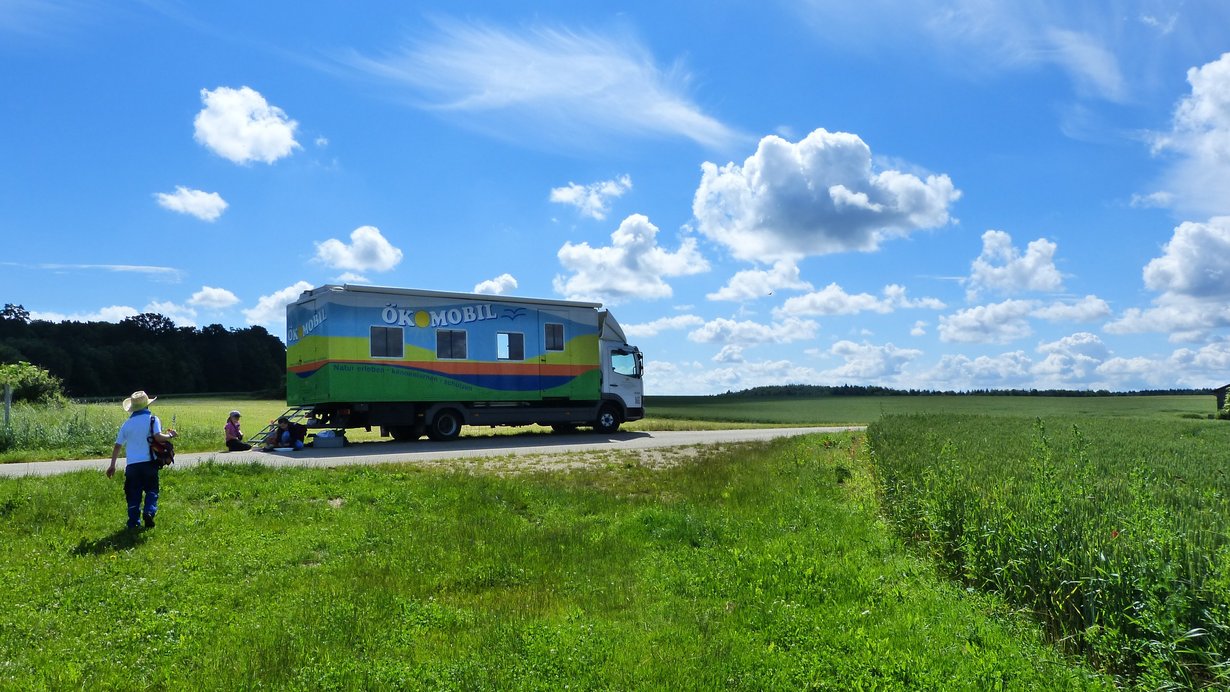 Ökomobil Tübingen steht auf einer wiese, dahinter ist ein tiefblauer Himmel