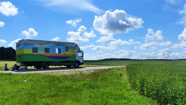 Ökomobil Tübingen steht auf einer wiese, dahinter ist ein tiefblauer Himmel