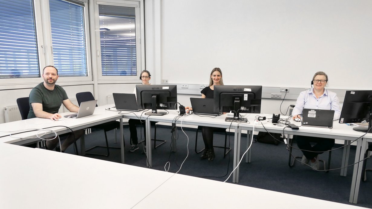 Kolleginnen und Kollege der Servicestelle Stoffliche Marktüberwachung sitzen zusammen in einem Besprechungsraum mit ihren Laptops