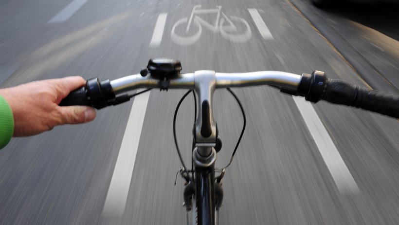 Blick über den Lenker:Fahrrad in schneller Fahrt auf einem Fahrradweg
