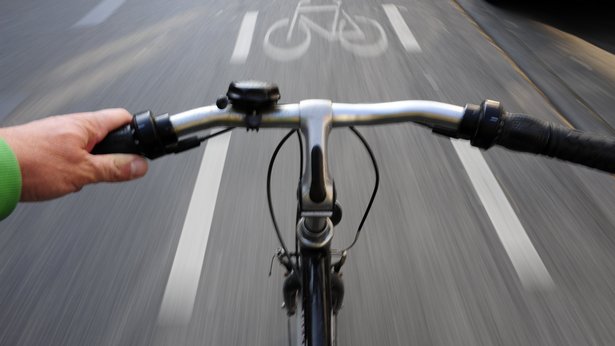 Blick über den Lenker:Fahrrad in schneller Fahrt auf einem Fahrradweg