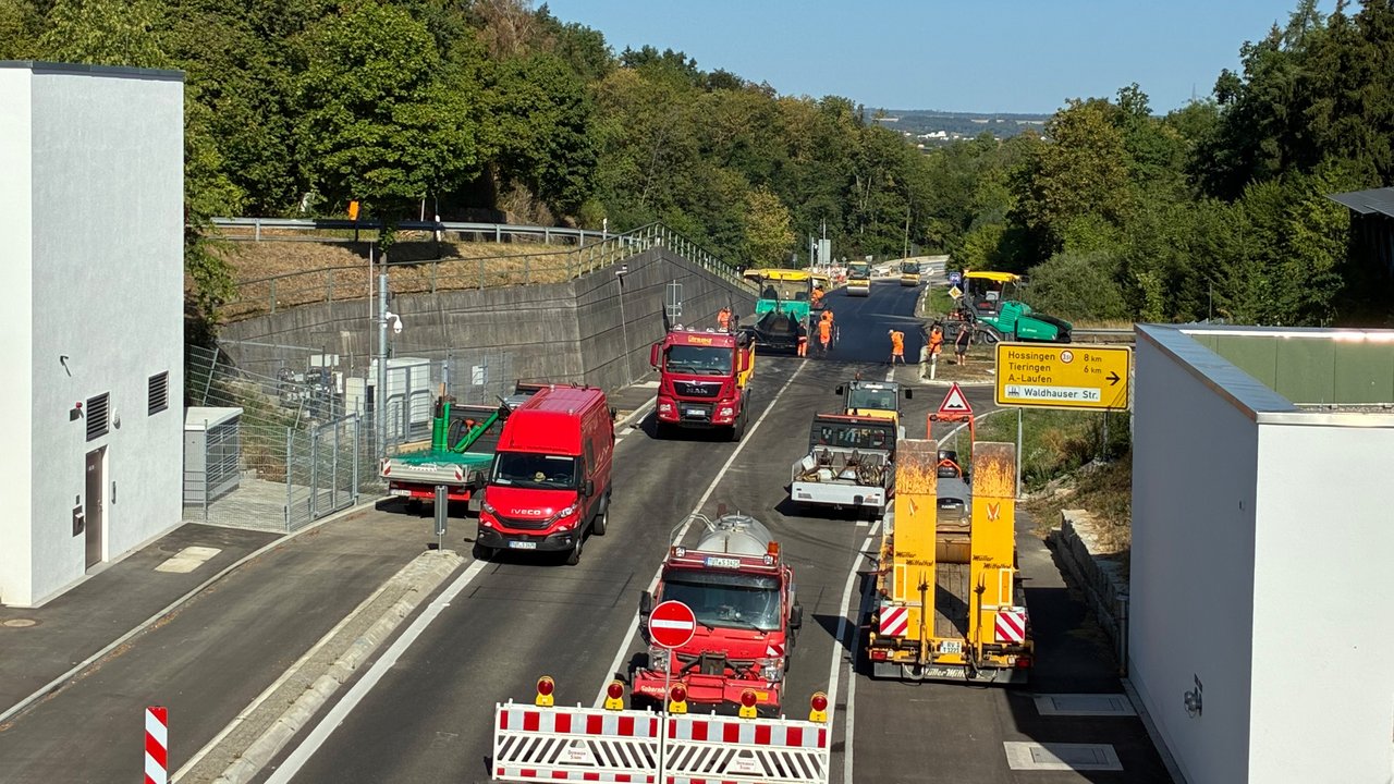 Das Foto zeigt Asphaltarbeiten auf der Eyachbrücke. Man sieht mehrere Baustellenfahrzeuge und einen neu asphaltierten Teil der Brücke.
