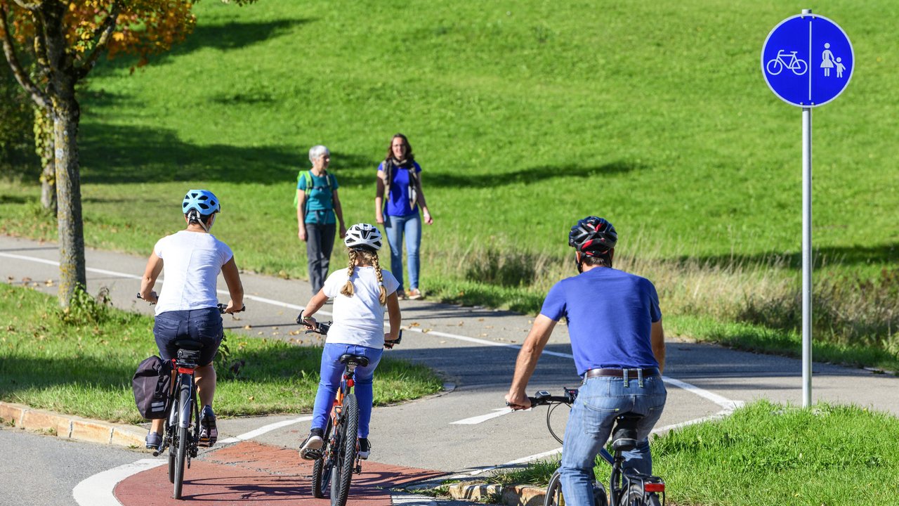 Radfahrer befahren einen Übergang von der Straße auf einen kombinierten Rad- und Fussweg