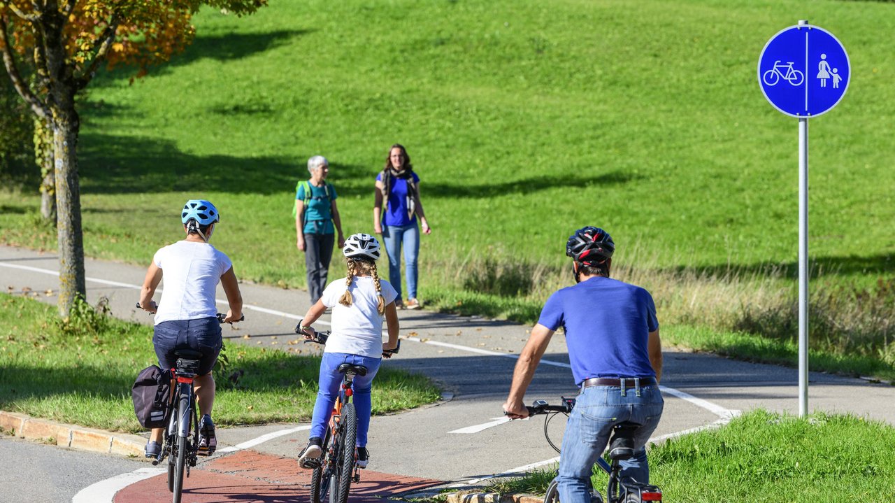 Radfahrer befahren einen Übergang von der Straße auf einen kombinierten Rad- und Fussweg