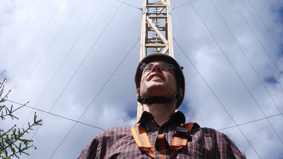 Mann in Sicherheitsbekleidung vor Sendemast Mann in Sicherheitsbekleidung vor Sendemast