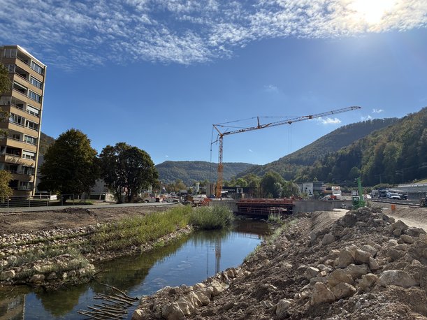 Fot eines Flusses. Im Hintergrund befindet sich eine Brückenbaustelle. 