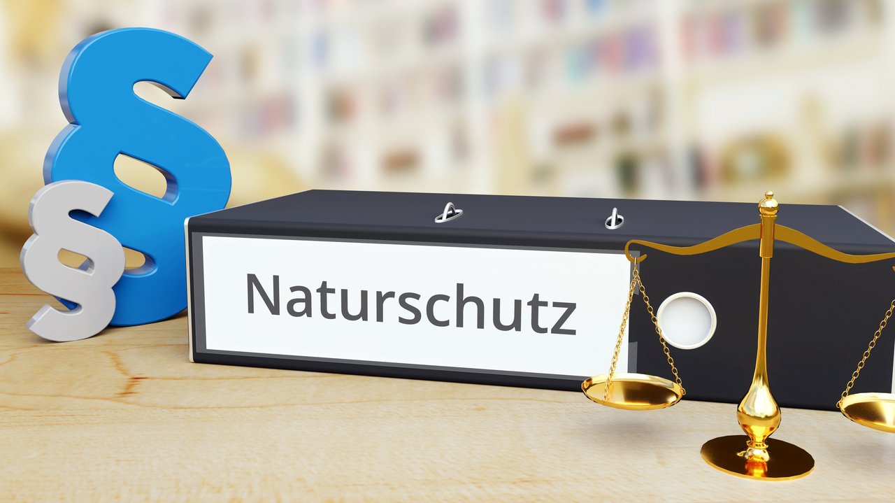 Das Foto zeigt einen Ordner mit der Aufschrift "Naturschutz". Links sieht man 2 Paragrafensymbole und rechts eine Waage